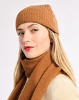 Woman wearing a brown knit hat and scarf on a white background