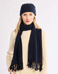 Woman wearing a navy scarf and beanie on a white background
