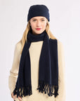 Woman wearing a navy scarf and beanie on a white background