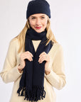 Woman wearing a navy scarf and hat on a white background