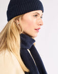 Woman wearing a navy blue knit hat and scarf on a white background