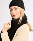 Woman wearing a black knit hat and scarf with a white background