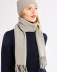 Woman wearing a gray knit hat and scarf on a white background