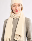 Woman wearing a cream beanie and scarf on a white background
