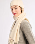Woman wearing a beige knit hat and scarf on a white background
