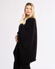 Woman wearing a black poncho over a white background