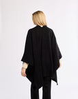 Person wearing a black poncho against a white background