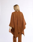 Person wearing a brown poncho and pants on a white background