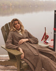 Woman modeling a long tweed coat in a chair outside