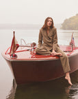 Woman sitting on a boat modeling a tweed blazer and pants