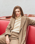 Woman modeling a long tweed coat sitting on a boat