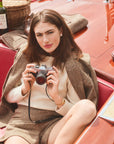 Woman modeling a tweed blazer and shorts while sitting on a boat