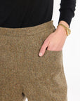 Close-up of a hand in the pocket of the Painter's Fleck Herringbone Archer Shorts, showing the waistband and tweed texture, photographed against a plain white studio background.