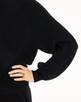 Close-up of the balloon sleeve, ribbed cuff, and knit texture of the black Baby Cashmere Ribbed Crewneck, photographed against a plain white studio background.