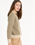 A woman modeling the Camel Tri-Color Check Classic Cashmere Cardigan with camel trousers, side view, photographed against a plain white studio background.