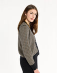 A woman modeling the Black Tri-Color Check Classic Cashmere Cardigan with black trousers, side view, photographed against a plain white studio background.