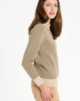 A woman modeling the Camel Tri-Color Check Classic Cashmere Crew with camel trousers, side view, photographed against a plain white studio background.