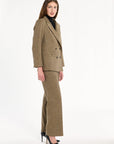 A woman modeling the Painter's Fleck Herringbone Cynthia Blazer with matching trousers, side view, photographed against a plain white studio background.