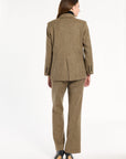 A woman modeling the Painter's Fleck Herringbone Cynthia Blazer with matching trousers, back view, photographed against a plain white studio background.