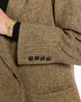 Close-up of the buttoned cuff, pocket, and flecked herringbone texture of the Cynthia Blazer, photographed against a plain white studio background.