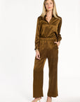 A woman modeling the Golden Umber Diane Pants with the coordinating Eleanor Shirt and cream heels, full-length front view, photographed against a plain white studio background.