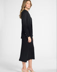 Woman modeling a long sleeve black cardigan over the matching black shell and skirt on a white backdrop