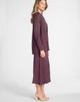 Woman wearing a pleated purple cardigan and skirt on a white backdrop