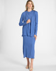 Woman modeling a blue pleated cardigan with gemstone buttons on the sleeve on a white backdrop