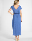 A woman modeling a blue midi dress from the back, featuring a V-neckline, short sleeves, a matching fabric tie belt at the waist, and a scalloped hem, set against a plain light gray studio background.