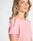 Close up of a pleated dress shoulder showing pink quartz gemstones on the shoulder