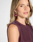 Woman modeling a pleated shell with purple quartz gemstone buttons on the shoulder on a white backdrop