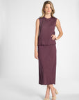 Woman modeling a purple pleated shell and the matching skirt on a white backdrop