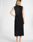 A woman shown from the back wearing a sleeveless black midi dress with a ruffled hem, paired with beige high heels, against a white studio background.