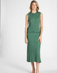 Woman modeling a sage green pleated skirt and shell on a white backdrop