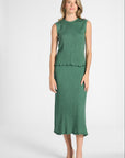 Woman modeling a sage green pleated skirt and shell on a white backdrop