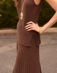 Woman wearing a brown ribbed knit skirt and matching top outside on a street with gold jewelry