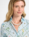 Woman wearing a light blue floral dress and pearls with a white background