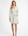 Woman modeling a mid-length white floral dress on a white backdrop