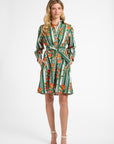 Woman modeling a green striped dress with oranges on a white backdrop