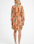 Woman wearing an orange and green patterned dress on a white background
