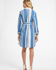 Woman wearing a blue and white striped dress with white heels on a white background