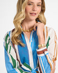 Woman wearing a colorful, striped, long sleeve dress with a plain background