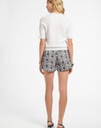 Woman wearing a white cotton top and patterned shorts on a white background