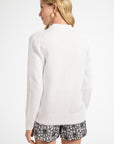Woman wearing a white long-sleeve cardigan and patterned shorts on a white background