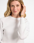 Woman modeling a white sweater on a plain background