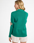Woman wearing a green sweater and white shorts on a white background
