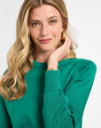 Woman modeling a green crewneck sweater against a white background
