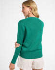 Woman wearing a green sweater and white shorts on a white background
