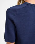 Navy blue short-sleeve top worn by a person on a white background