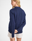 Woman wearing a navy cardigan sweater and white shorts on a white backdrop